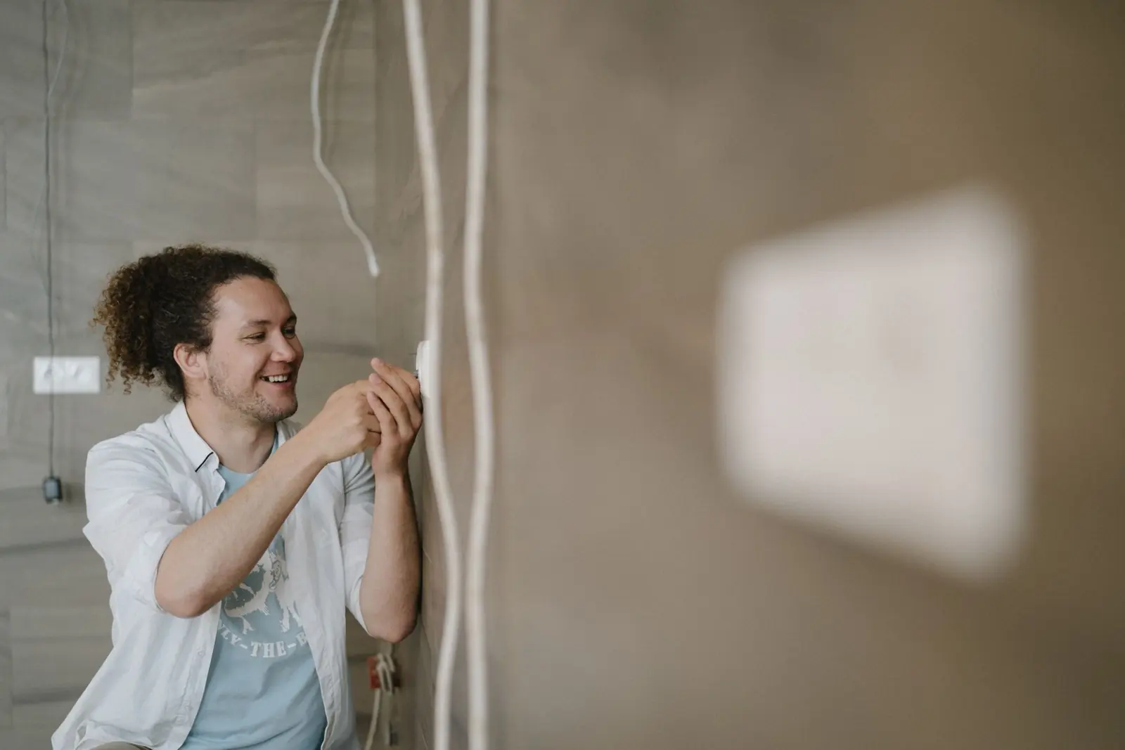 Smiling residential electrician installing an outlet in a St. Charles County home