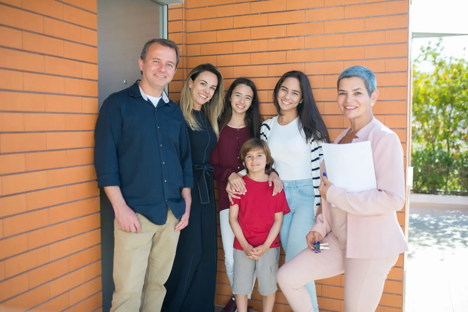 Family and their contractor smiling outside a new home