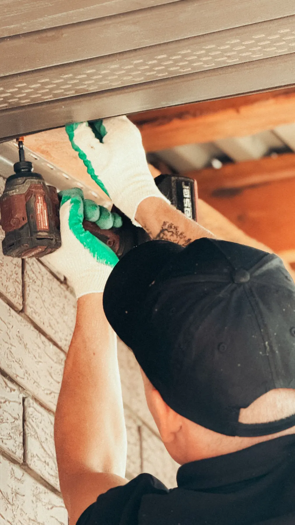 Electrician installing an exterior fixture under a roof overhang