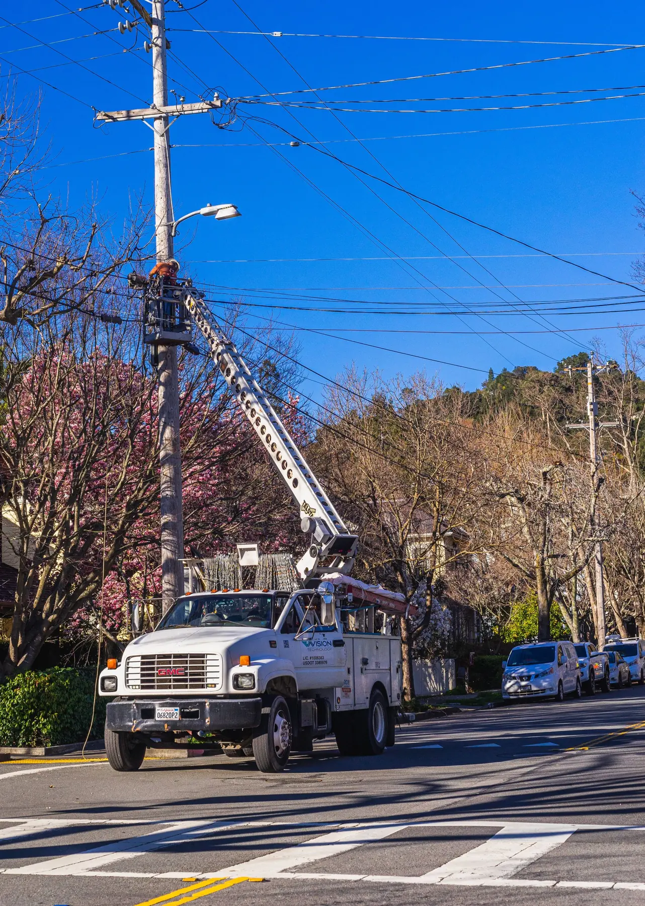 Utility bucket truck working on power lines along a tree-lined St. Louis-area street